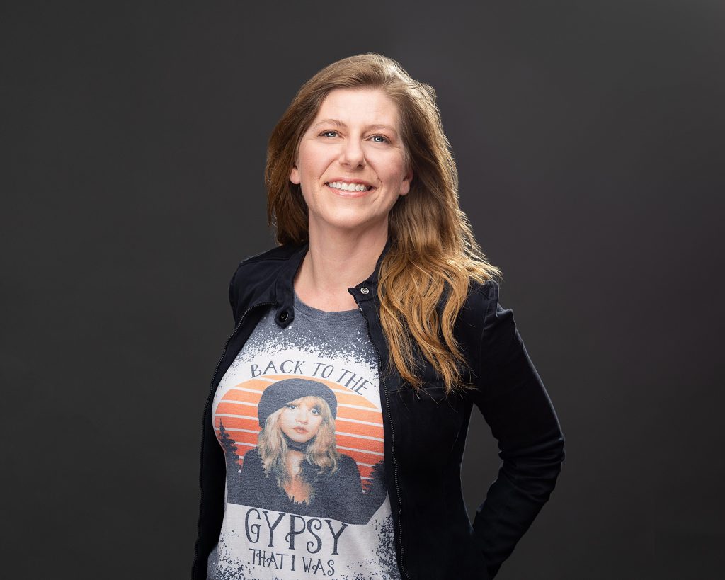 Business headshot photo of a smiling woman with long hair on a black backdrop in Berks County photo studio.