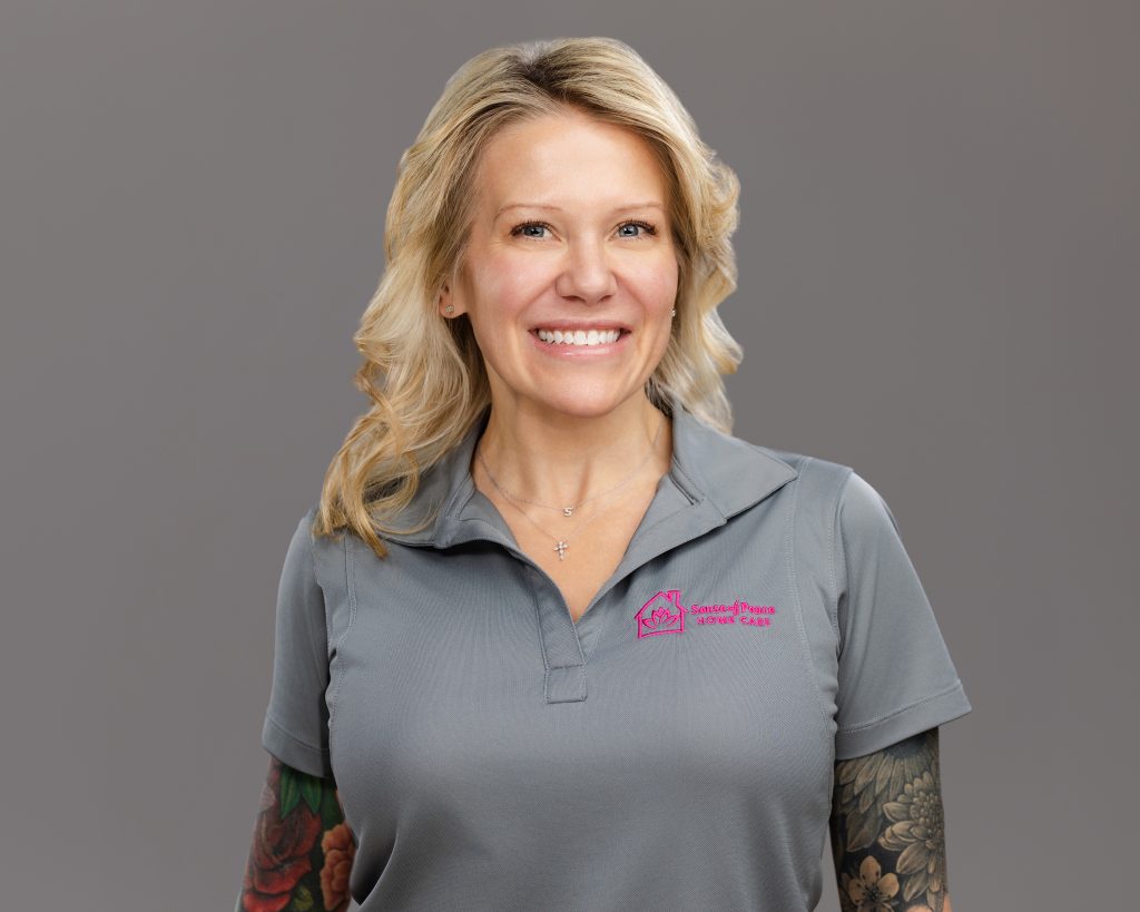 Home care staff photo of caregiver with blond hair and a grey polo on grey background