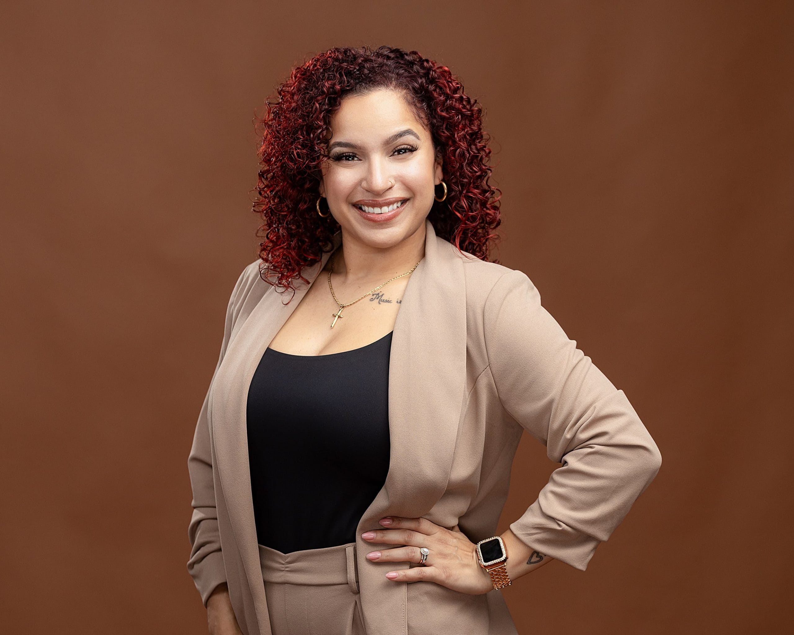 Professional photo of a smiling business woman with pink and black hair with a textured brown headshot background.