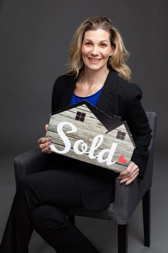 Real estate agent headshot holding a "SOLD" sign