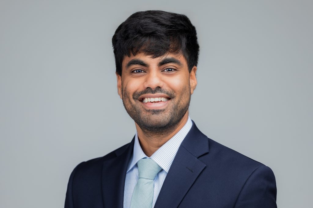 Headshot of a smiling male medical student wearing a suit and tie. 