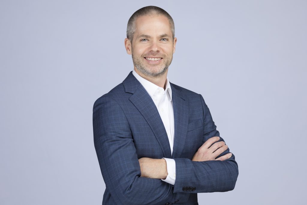 Business photo of Ben wearing a blue jacket and white shirt with arms crossed. 