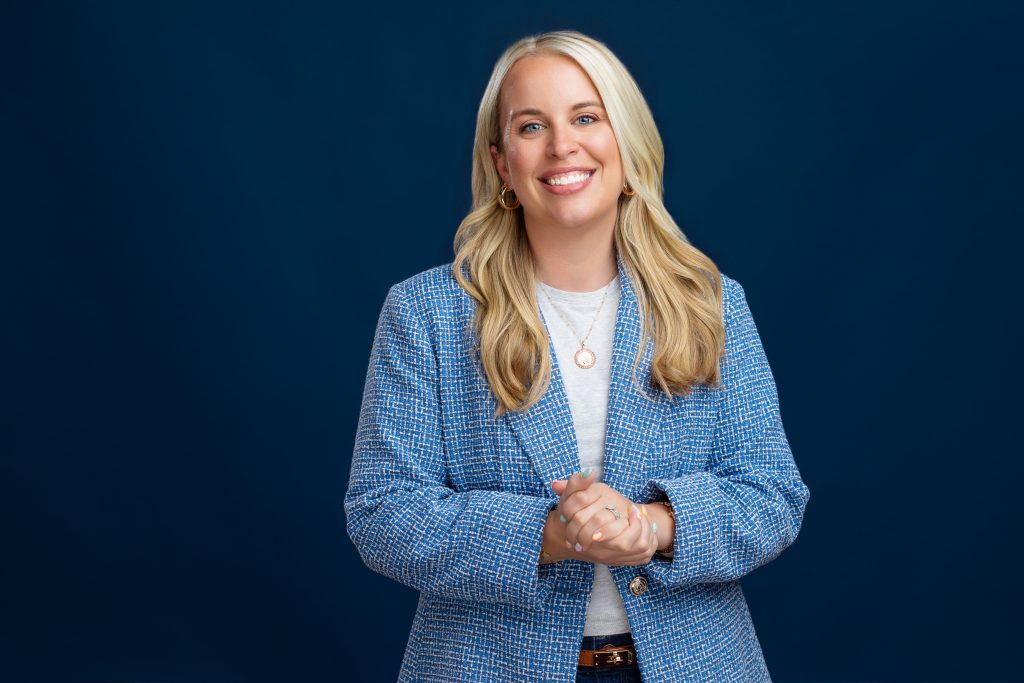 Berks real estate agent Taylor Ferretti wait-up headshot on dark blue background. 