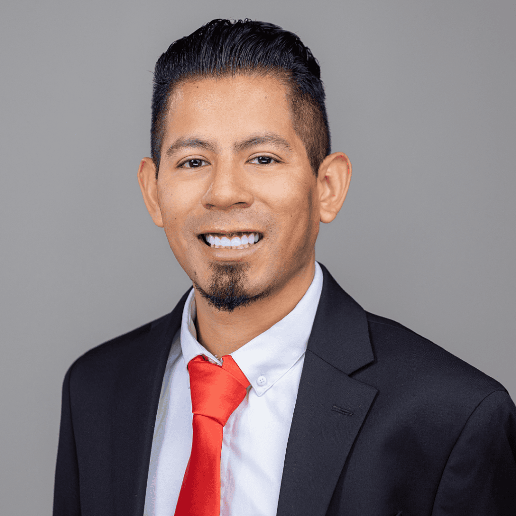 Professional headshot of a smiling man wearing a suit and smiling.