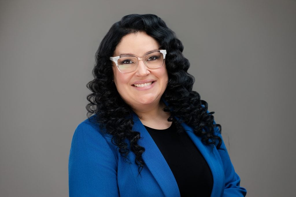 Business headshot of a smiling woman wearing a blue blazer 
